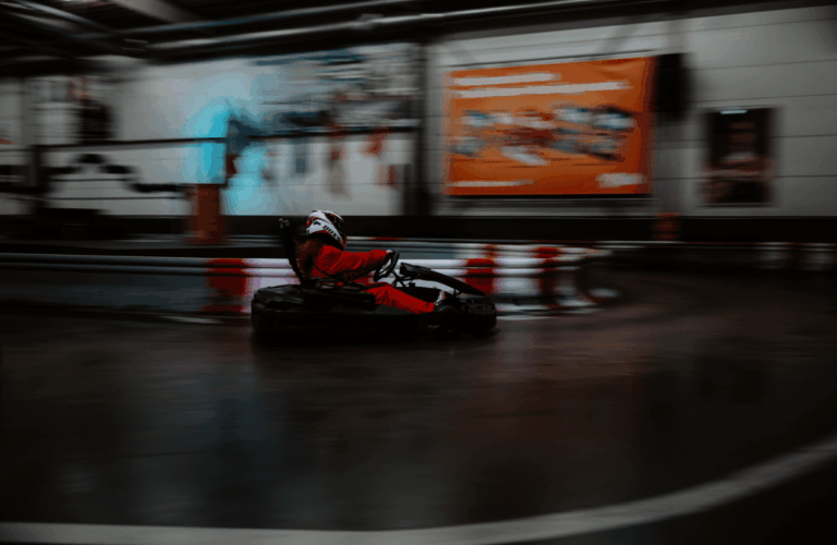 Ein Fahrer im roten Overall in einer Kurve von hinten auf der Rennstrecke im Kartcenter Cologne, Kartfahren Köln.
